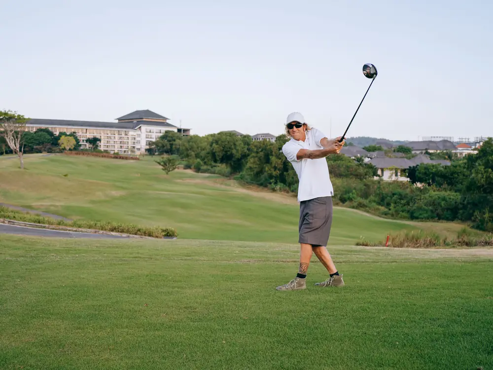 A golfer mid-swing on a lush green course